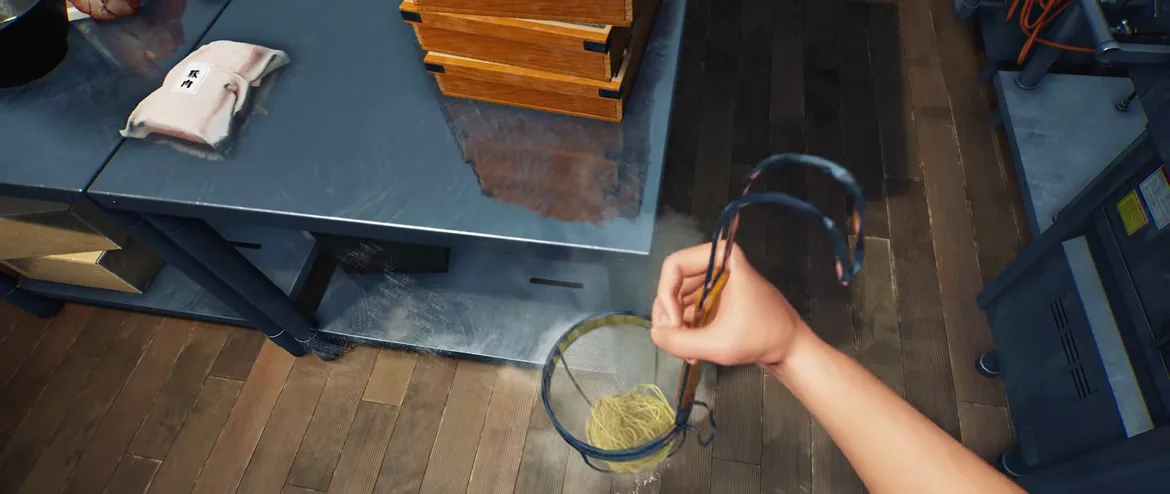 Overhead first-person view in Japanese Ramen Simulator of a hand lifting a wire strainer of cooked noodles over a stainless prep counter, with a vacuum-packed chashu portion labelled 豚肉 and stacked wooden noodle boxes beside it Overhead first-person view in Japanese Ramen Simulator of a hand lifting a wire strainer of cooked noodles over a stainless prep counter, with a vacuum-packed chashu portion labelled 豚肉 and stacked wooden noodle boxes beside it