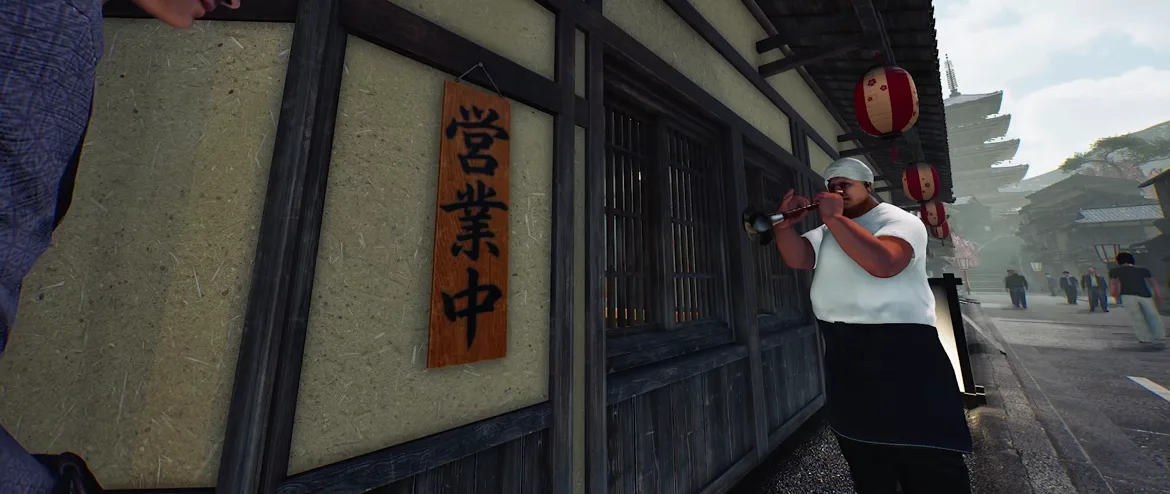 Japanese Ramen Simulator a wooden vertical sign with black brush-written Japanese characters for open for business hanging on the shop wall while a man in a white head wrap, black apron and sunglasses stands beside it holding a handled tool