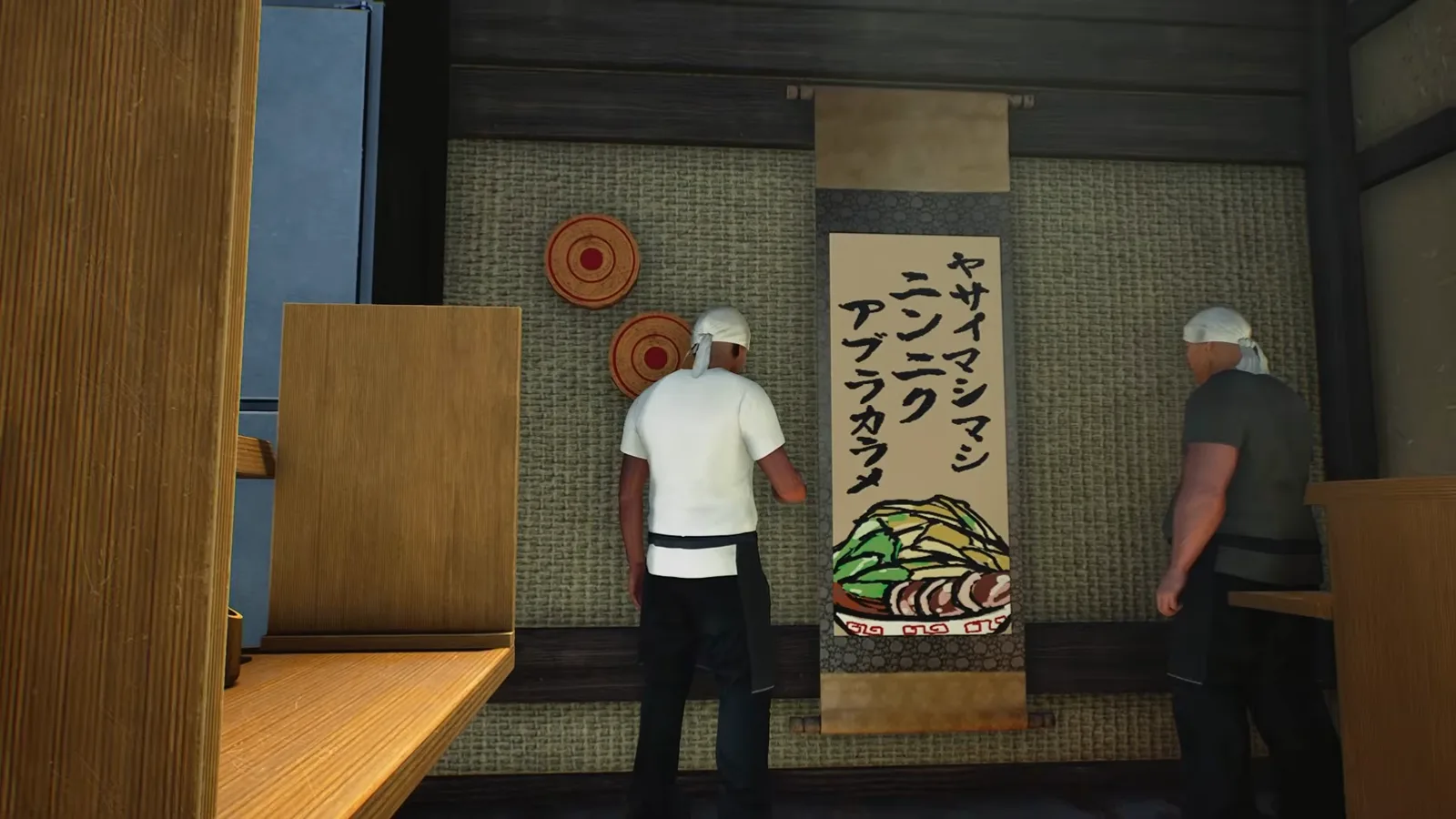 Custom hanging scroll on the wall of a Japanese Ramen Simulator shop with vertical brush text reading Yasai Mashimashi, Ninniku and Aburakare above a hand-drawn ramen bowl, a cook seen from behind