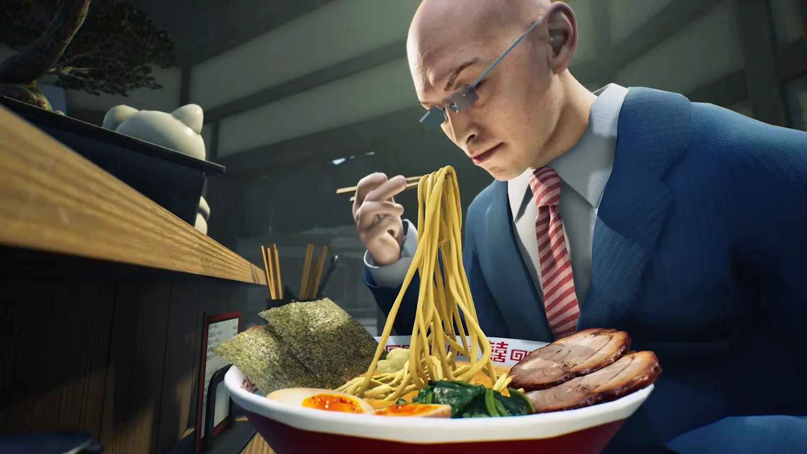 Bald customer in rimless glasses, a navy suit and red striped tie lifting yellow noodles from a red and white bowl in Japanese Ramen Simulator, with nori, ajitama, greens and chashu in the foreground