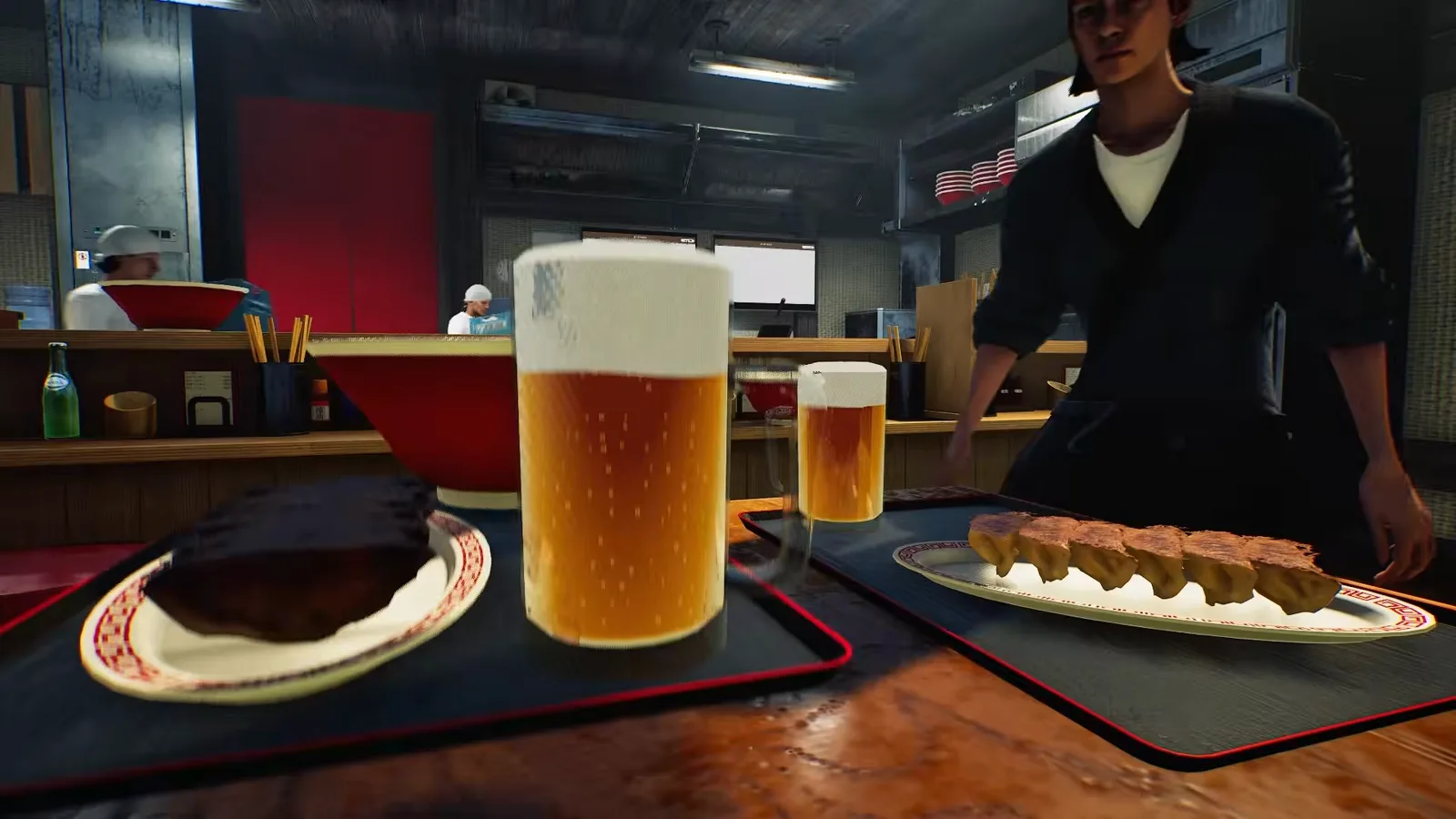 Table service in Japanese Ramen Simulator with two black red-rimmed trays holding a plate of five pan-fried gyoza and two foam-topped beer mugs, set down by a server in a black happi coat